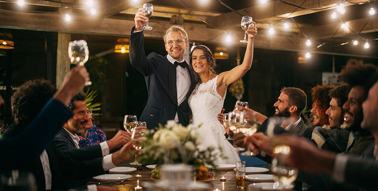 A bride and groom smile at each other while guests cheer